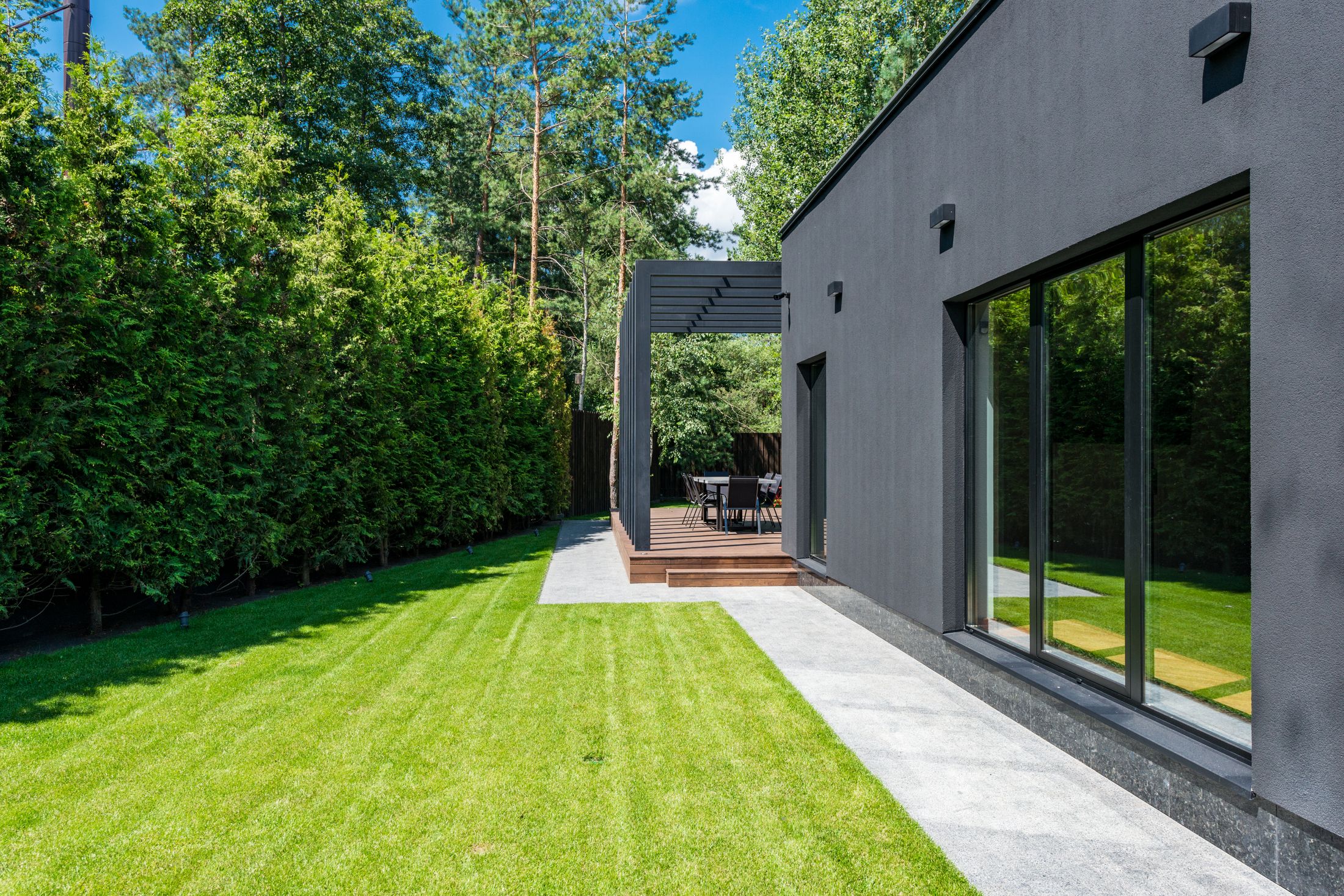 A low charcoal house opening onto a timber terrace and garden